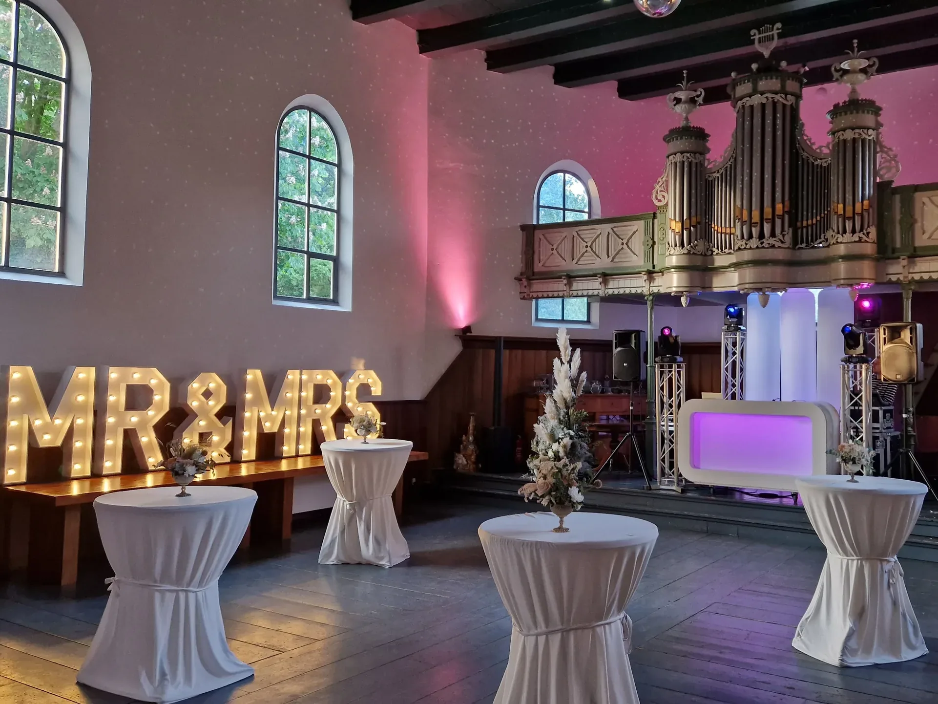 DJ-booth en verlichte MR&MRS-letters onder het orgel in De Amshoff in Kiel-Windeweer