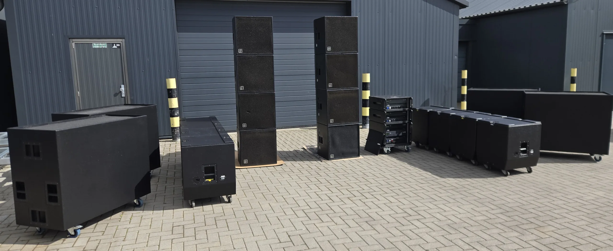 Opgebouwde d&b audiotechnik C4-geluidsset met subs op een binnenplaats