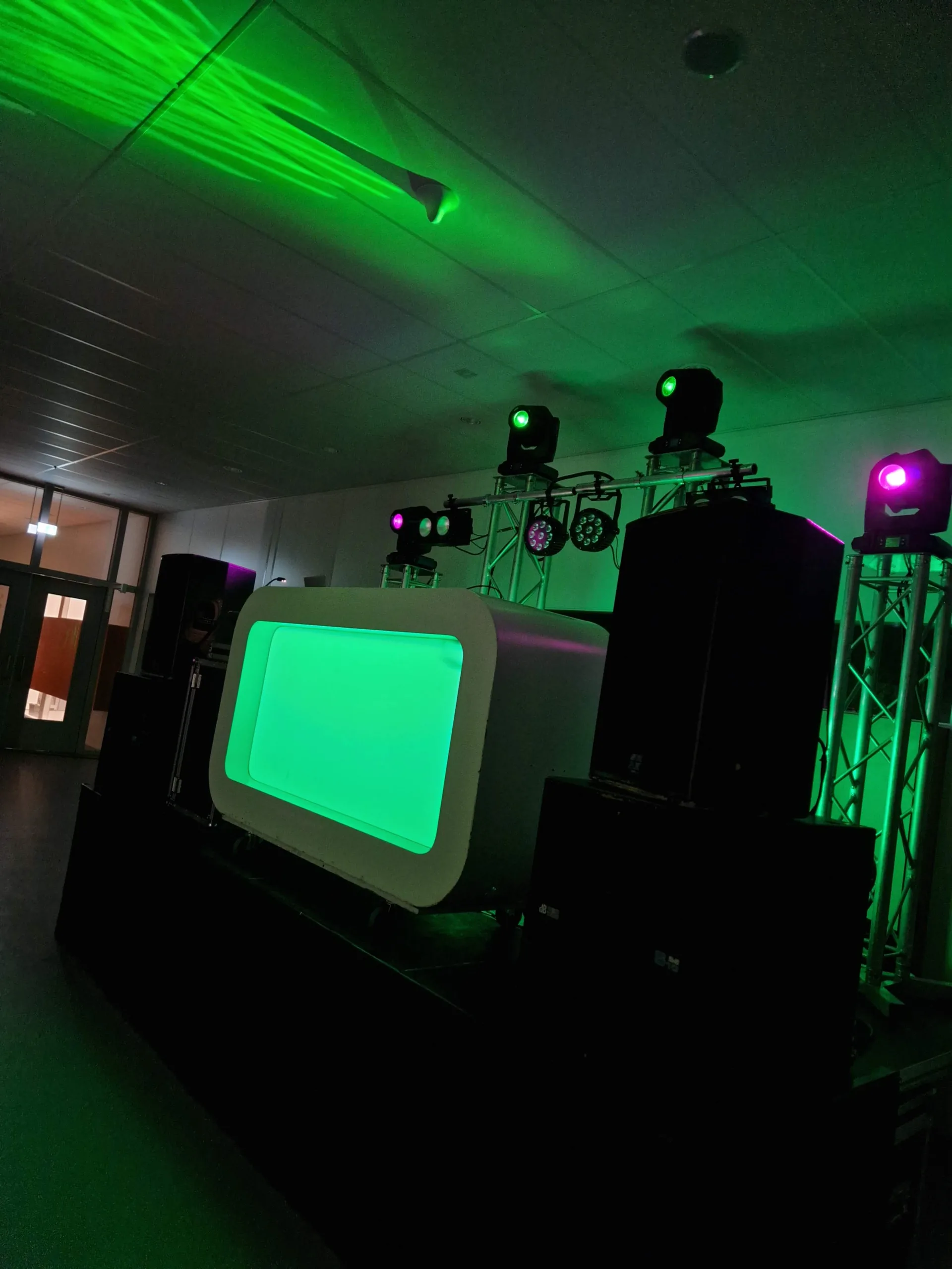 DJ-booth met moving heads en groene lasers in een schoolhal