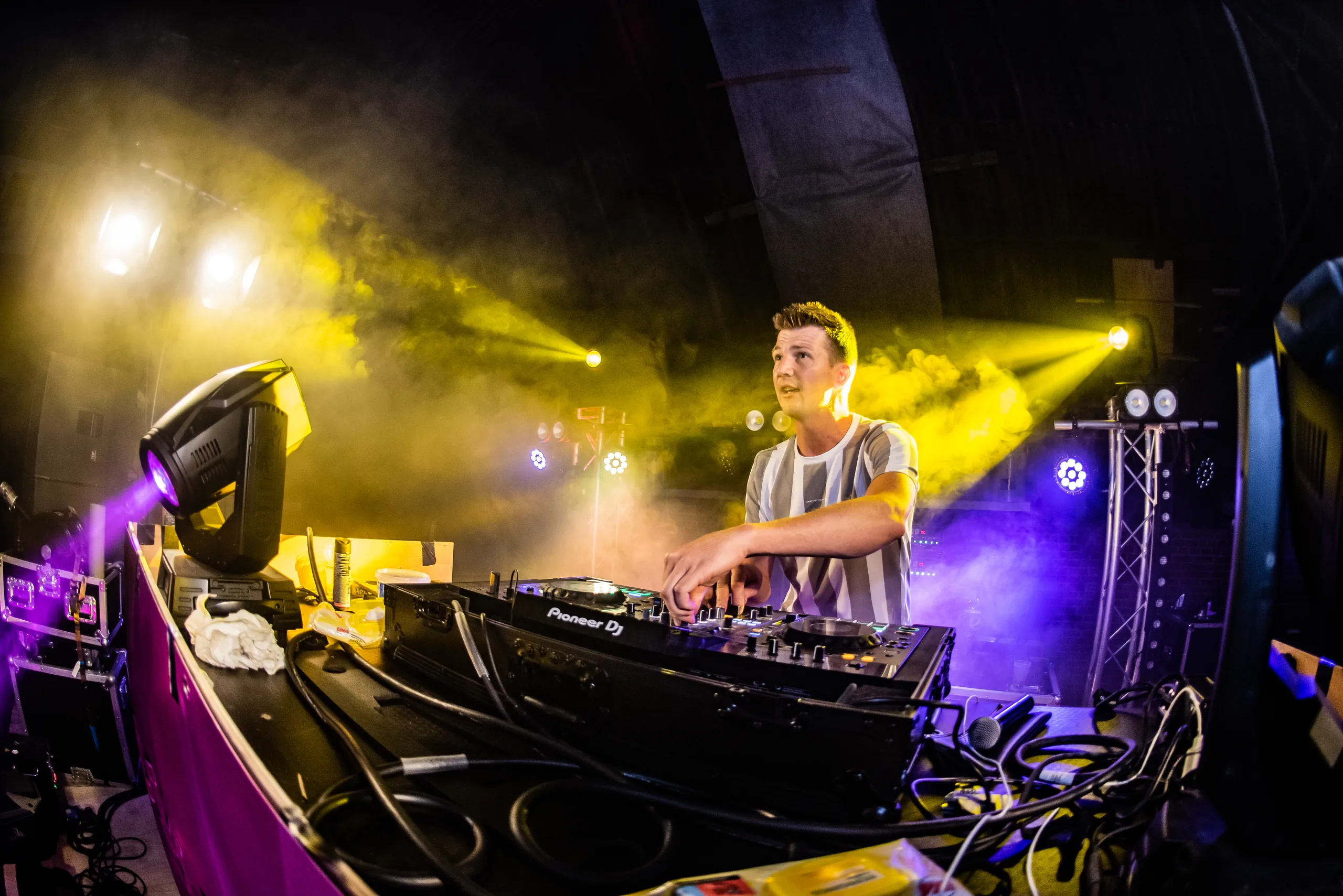 Martijn Alserda achter de booth in geel licht en rook