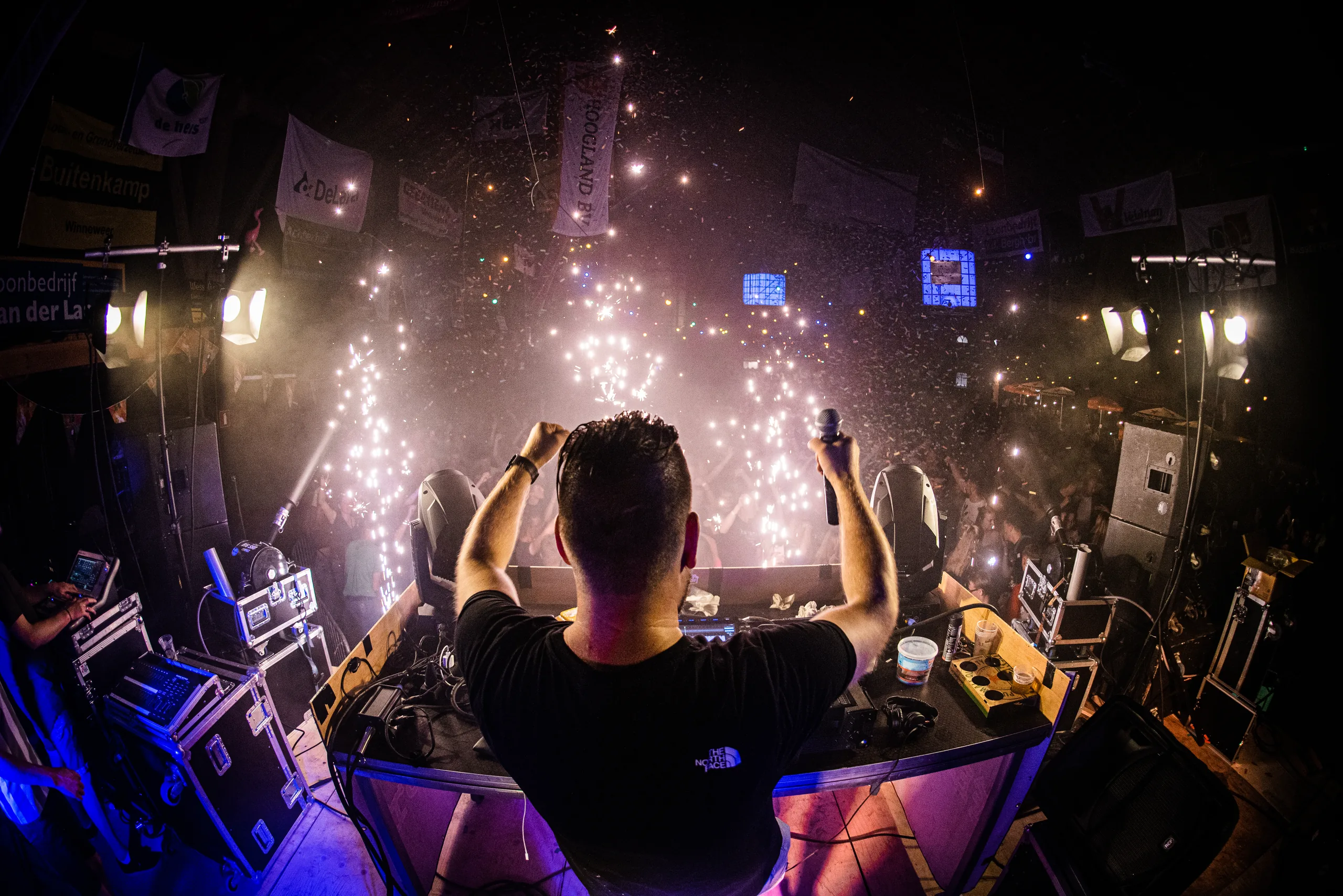 DJ Martijn Renkema van achteren gezien met sparkulars boven de volle dansvloer van een schuurfeest