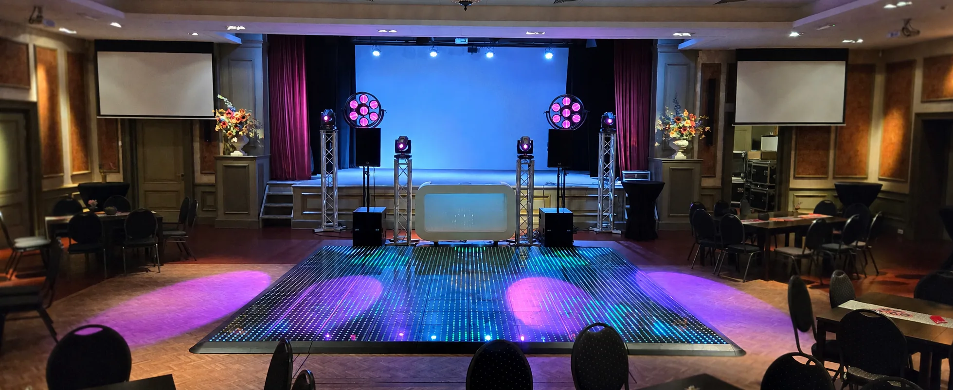 DJ-opstelling op een podium met een verlichte LED-dansvloer ervoor in De Postwagen in Tolbert