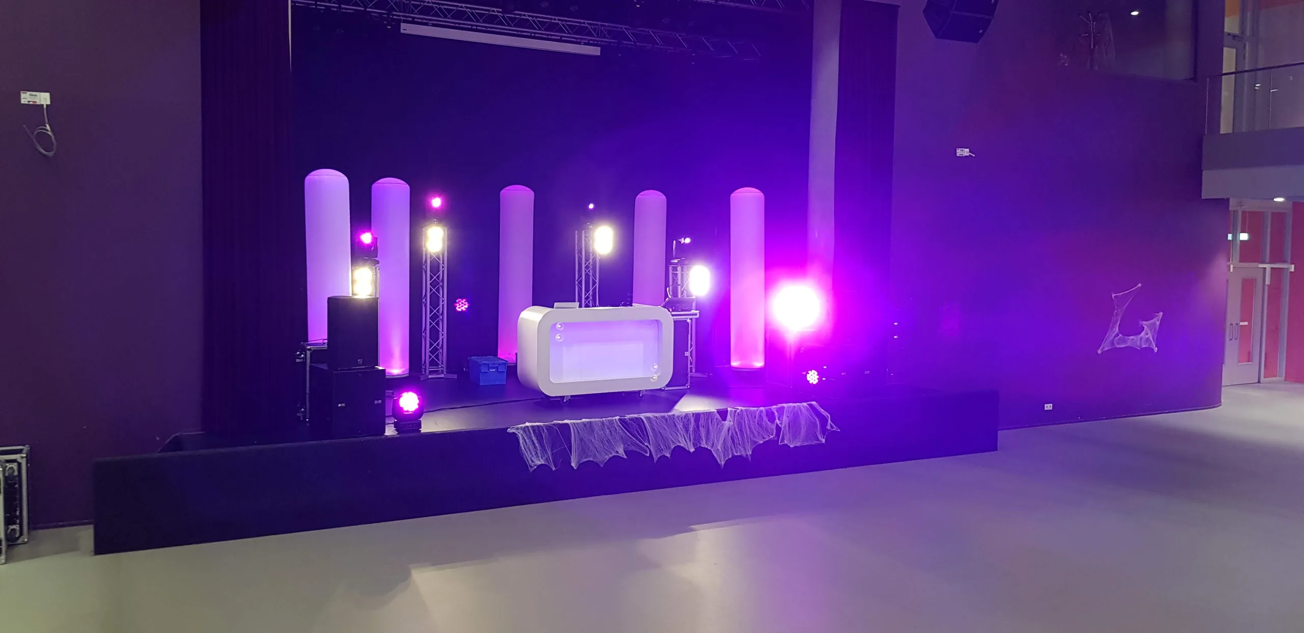 DJ-show met paarse lichtzuilen op het podium van een schoolaula