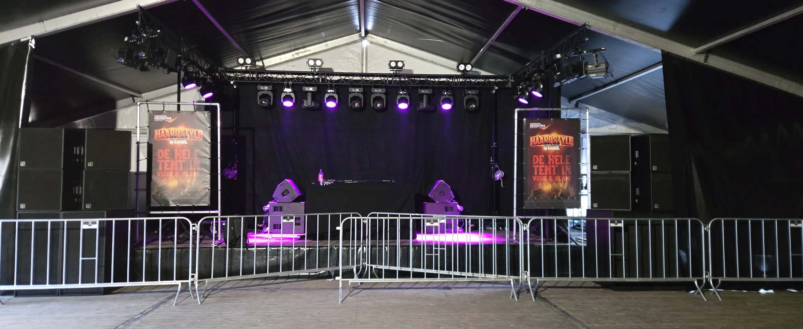 Opgebouwd podium met speakerstacks en lichttruss op een festivalterrein