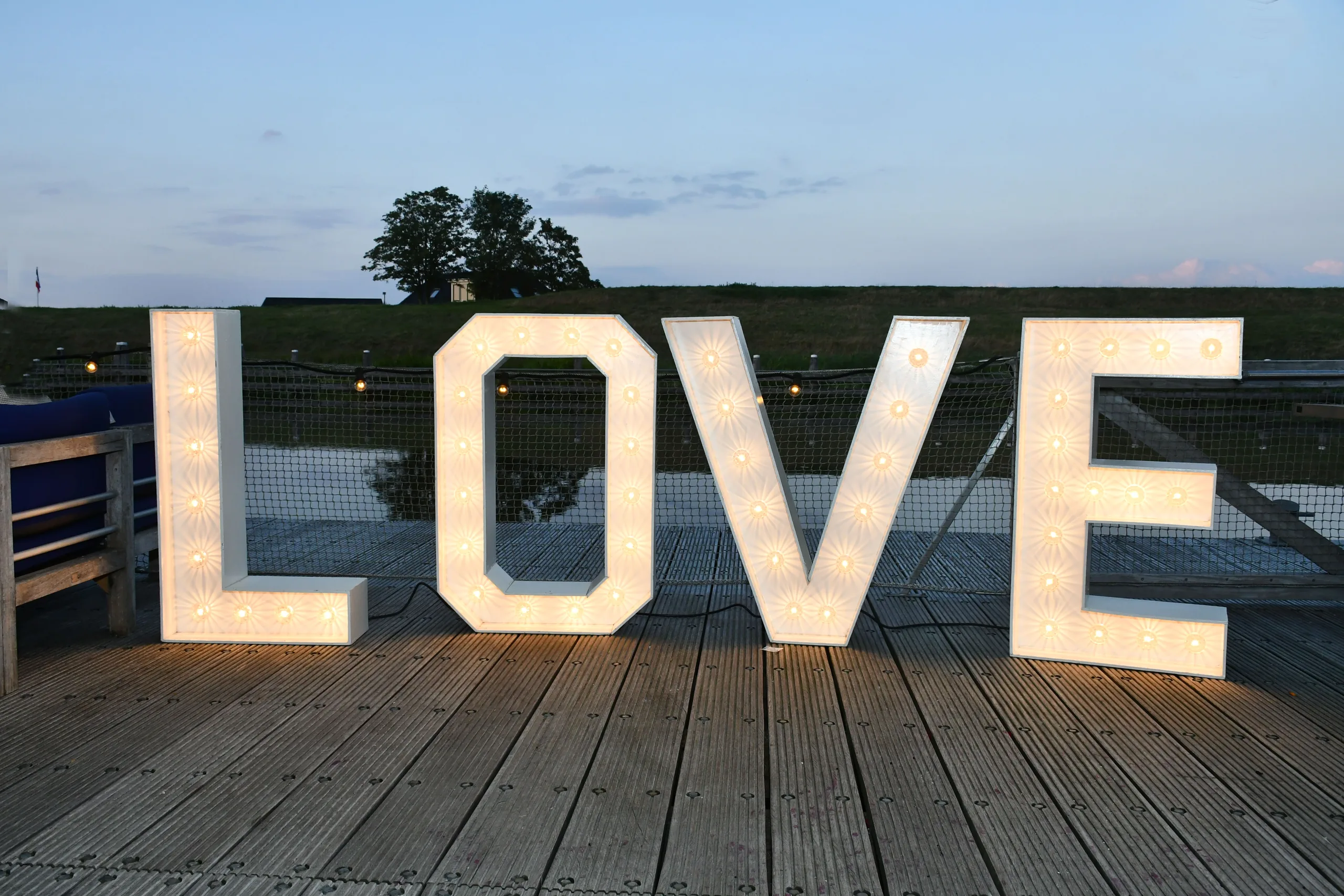 Verlichte LOVE-letters op het houten terras van Garnwerd aan Zee in de schemering