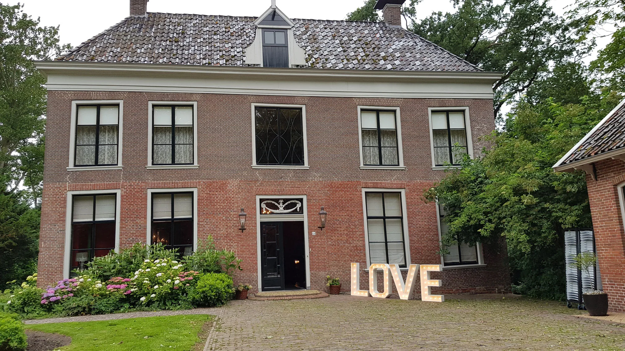Verlichte LOVE-letters op het erf voor de ingang van een Groningse borg