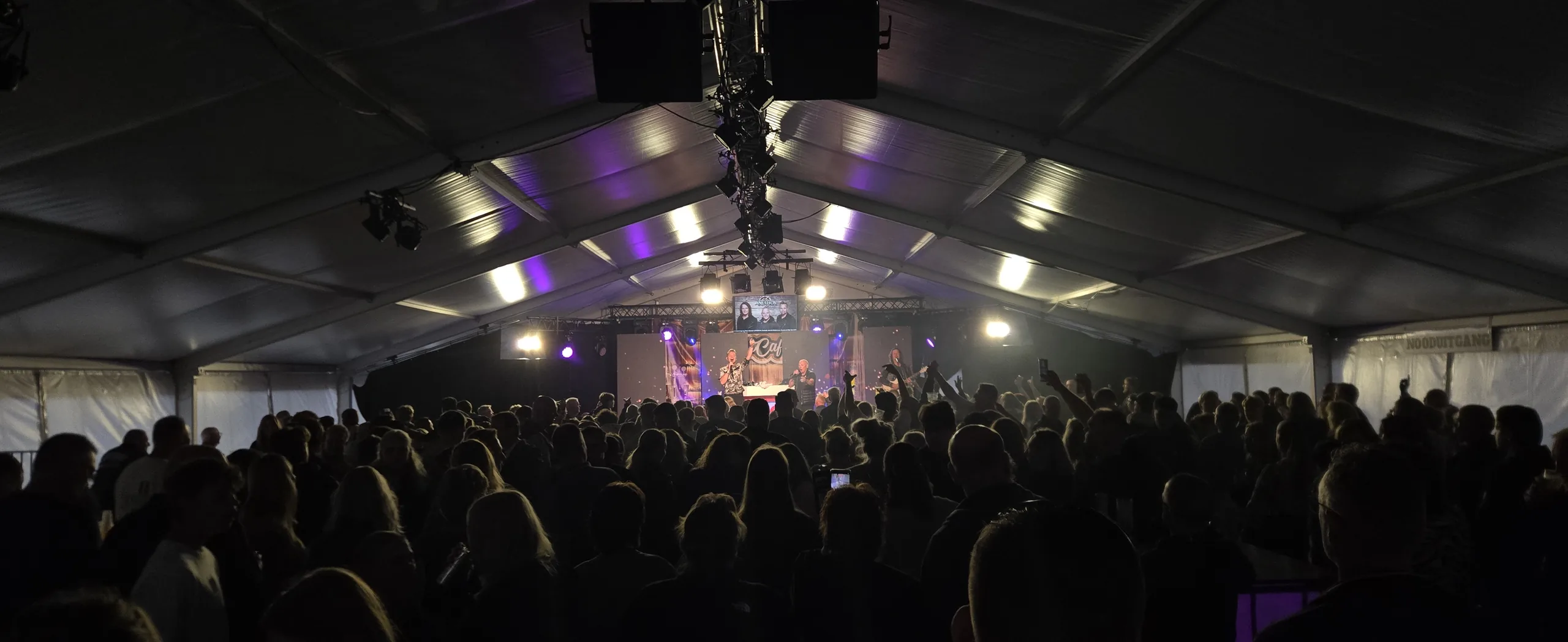 Publiek in de feesttent kijkt naar het podium tijdens het zomerfeest in Hoogkerk
