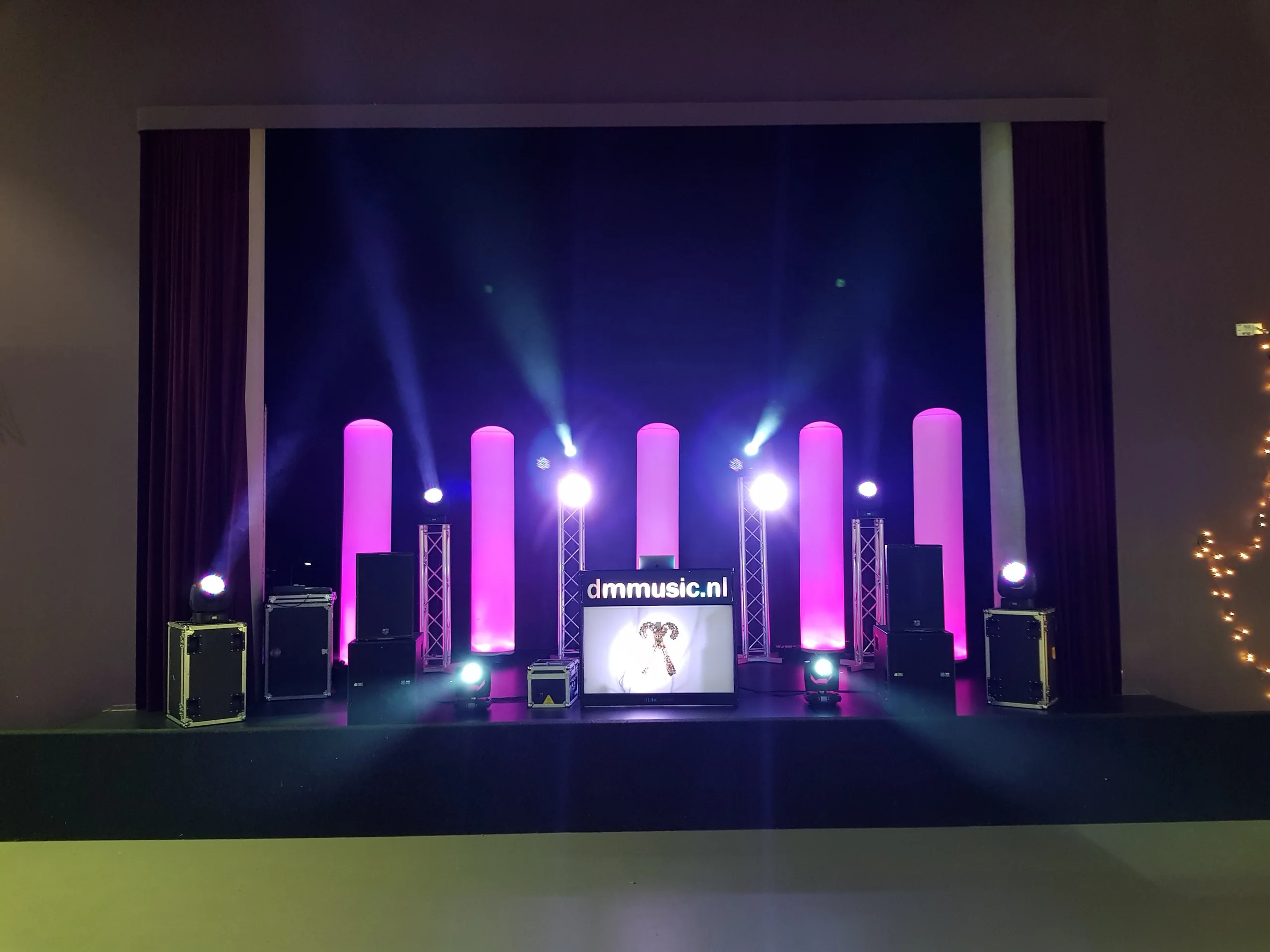 Podium met roze lichtzuilen en DJ-booth tijdens het schoolfeest in Haren