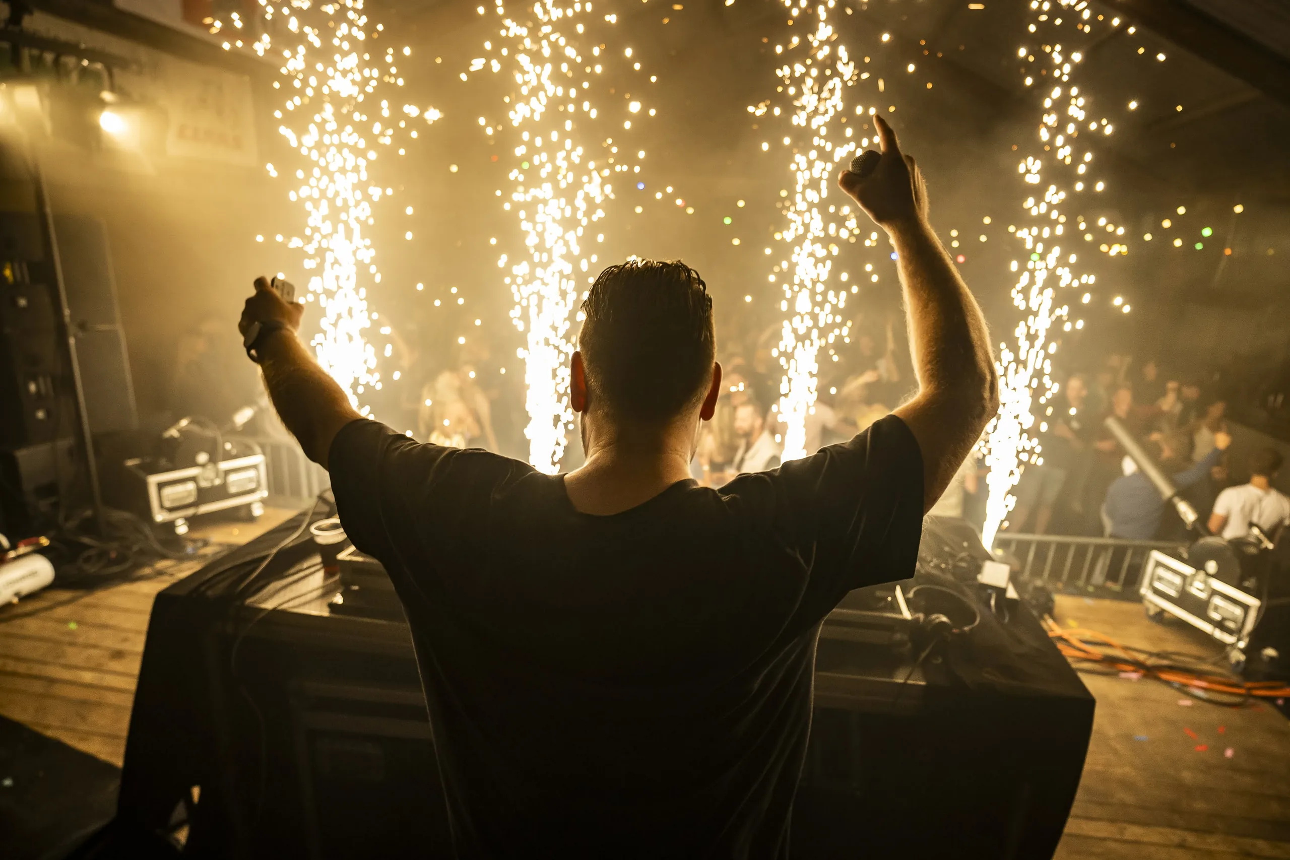 Vier vonkenfonteinen achter de DJ-booth boven het publiek