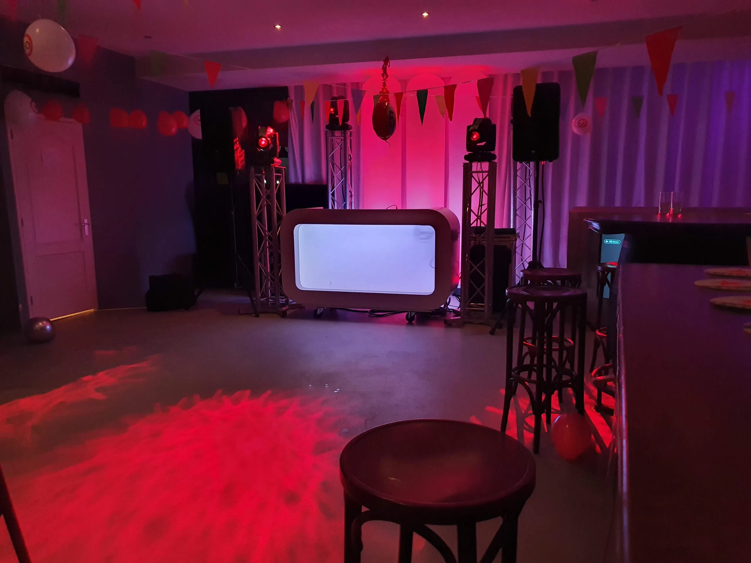 Verlichte DJ-booth onder rood licht in een zaal, klaar voor een verjaardagsfeest