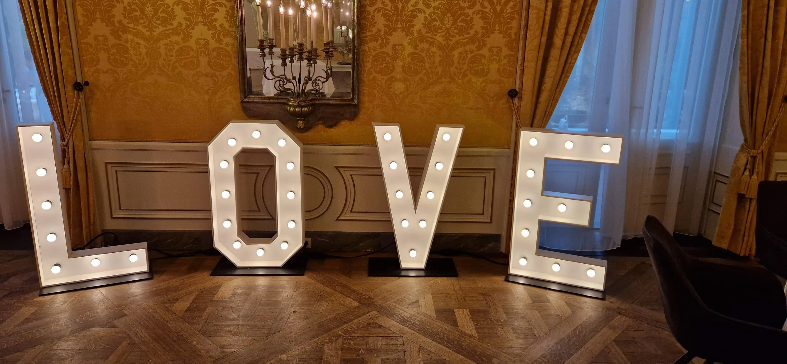 Verlichte LOVE letters in een zaal met goudkleurig behang