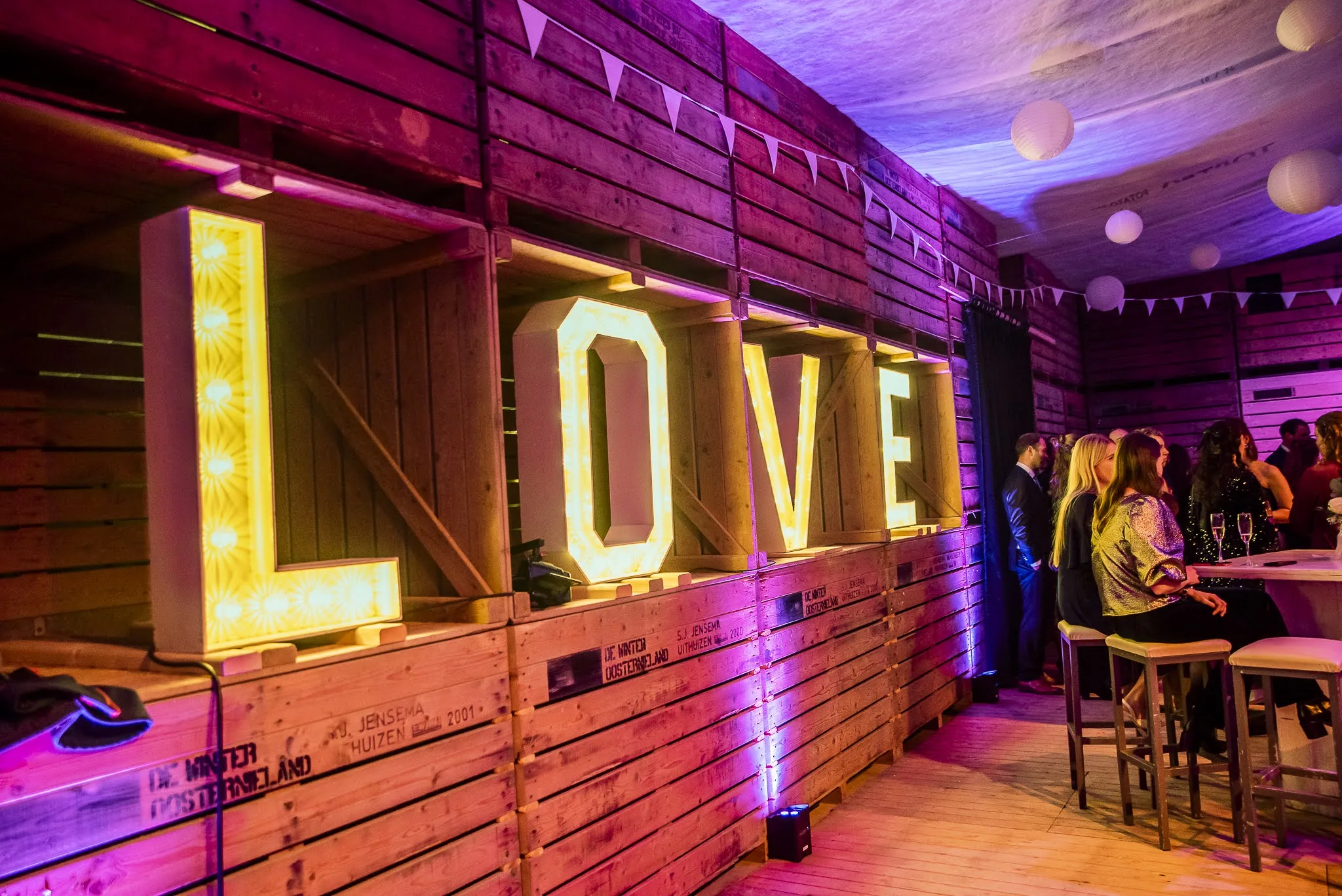 Verlichte LOVE letters tegen een houten wand met paarse uplights